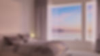 Bedroom with large window overlooking calm ocean at sunset