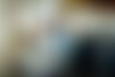 Three women look at sticky notes on a wall in a modern industrial office