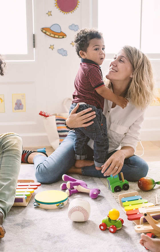 Montessori Daycare Teacher cuddling a child and assisting him in educational play
