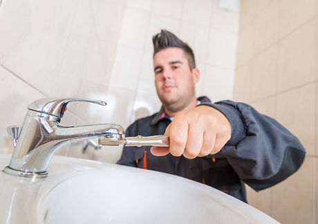 A uniformed plumber fixing a dripping tap