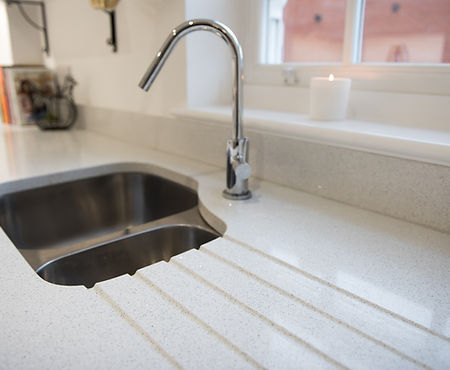 A general view of a sunken cut out stainless steel sink drainer in a quartz worktop in a kitchen
