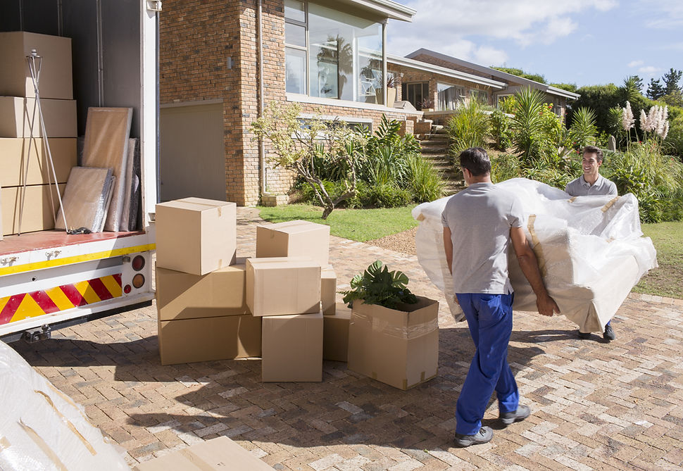 Two movers carrying a large sofa wrapped in brown protective fabric from a white van towards a house