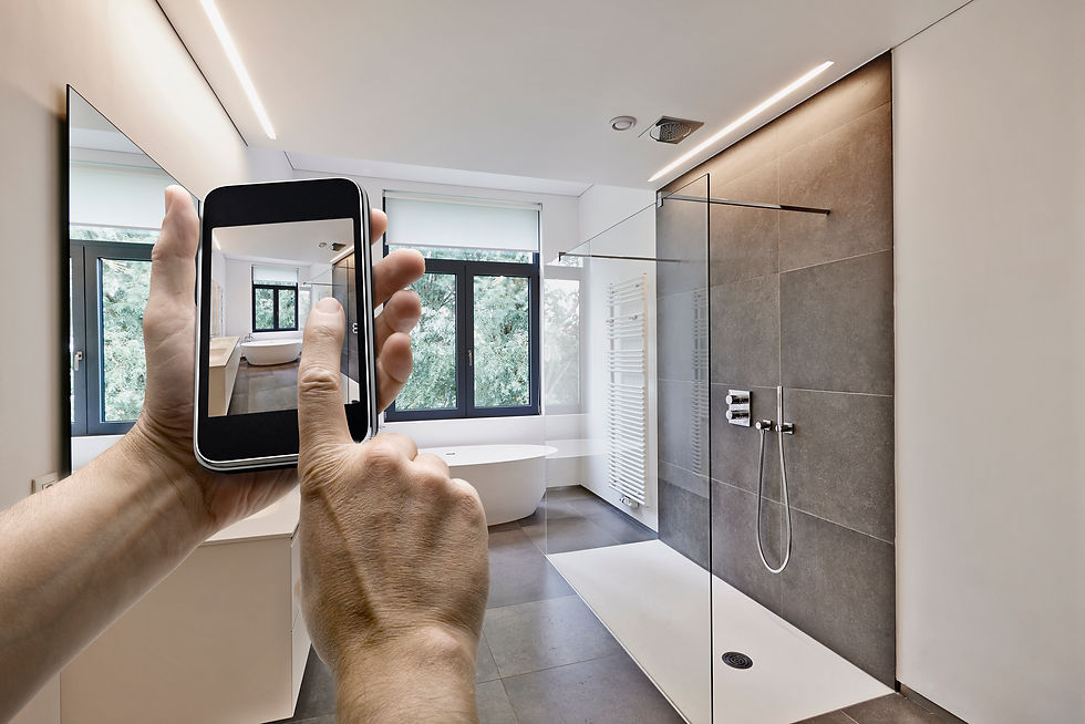 Hand holding phone to photograph a modern walk-in shower bathroom