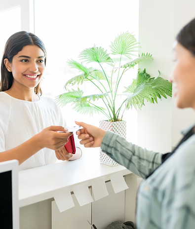 One woman paying another woman as they exchange cards.