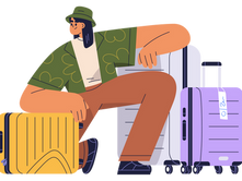 Person sitting with yellow and purple suitcases, wearing a green hat and shirt with patterns. Relaxed mood on a plain background.
