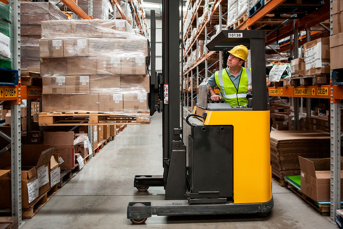 Forklift instructor in high-visibility vest supervising a trainee in a UK distribution centre