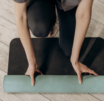 Eine Frau rollt Fitnessmatte aus, bereit für ein Gruppentraining in Leoben.