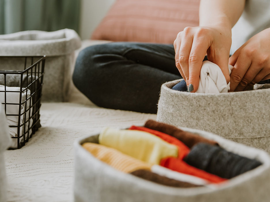 hands organizing clothes in a small felt storange bin