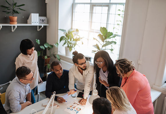 Diverse team gathered around a table, engaged in discussion in a contemporary office space.