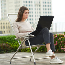 Woman working using her laptop while sitting on a folding chair