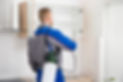 A worker using a sprayer to disinfect wooden cabinets in the kitchen