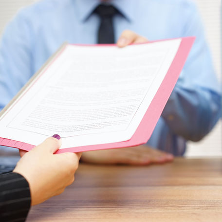 Two hands exchange a document in a pink folder