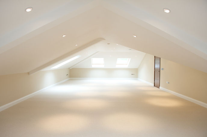 Bright empty loft conversion interior showing freshly painted sloped ceilings and modern skylights