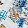 A pile of various pills and tablets scattered on a white surface.