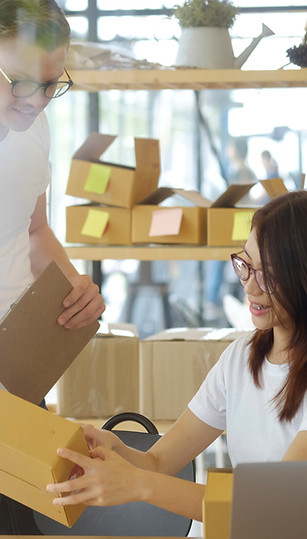 A man and a woman packing merchandise for delivery
