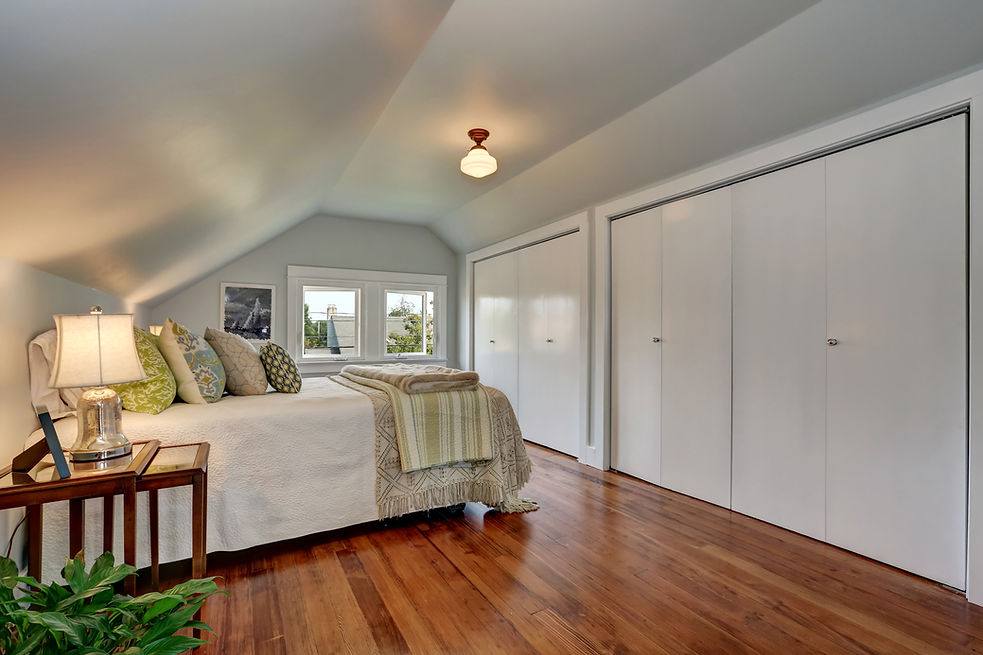 Attic bedroom interior with vaulted ceiling and hardwood floor