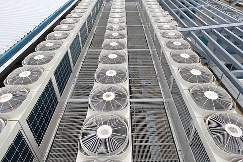 Row of large industrial air conditioning units with visible fan blades
