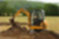 Mini digger moving earth in a field in rural countryside
