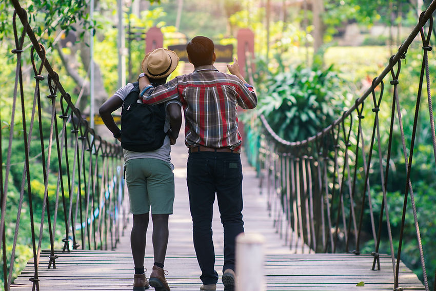 Two people walking together across a suspension bridge in a lush green setting, symbolizing BridgeCMO partnering with B2B tech companies to navigate marketing challenges