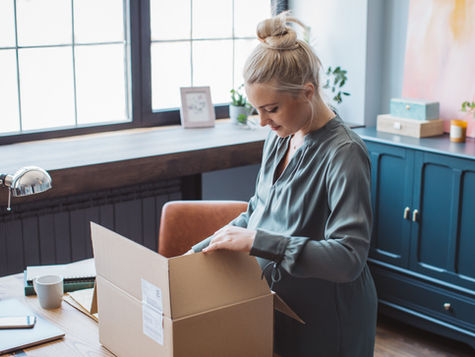Woman unpacking a boxe in a new home while updating their address with services.