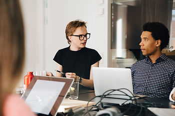 Two professionals engaged in a focused discussion at a modern workspace, reflecting the theme of the article 'Breaking the Bias Barrier: How Unconscious Prejudices Shape Our Workplace Decisions,' with one explaining points on a laptop as the other listens attentively.