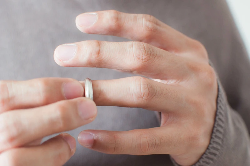 Close-up of a person sliding a silver ring off their finger.
