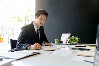 ผู้ชายกำลังเซ็นต์เอกสารบนโต๊ะทำงาน