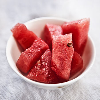Freshly cut watermelon cubes in a white bowl, offering a juicy and refreshing treat.