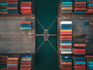 Aerial view of a busy container port with stacked shipping containers and cargo loading infrastructure, representing global trade, supply chain resilience, logistics, and international commerce.