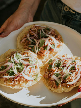 Three tostadas with meat, red onion, and cilantro on a plate