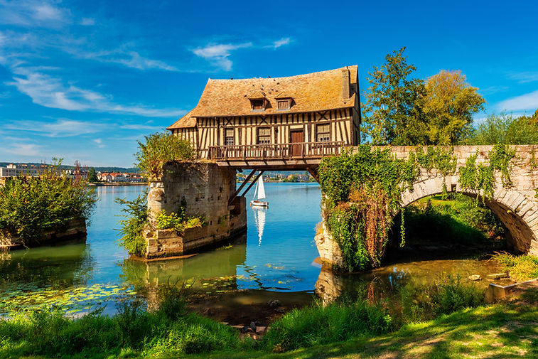 Maison à colombages suspendue sur pont en pierre, symbole du défi structurel et de préservation du patrimoine architectura