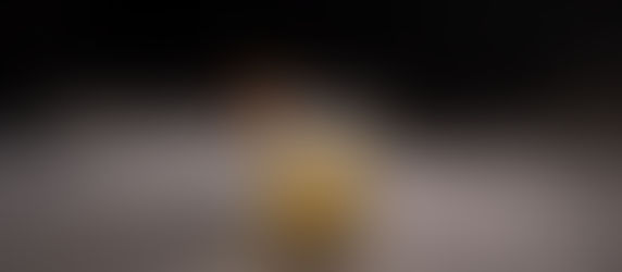 A cocktail in a crystal glass with salt rim and pear garnish sits on a misty surface. Dark background enhances its elegant look.