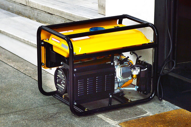 Yellow portable petrol generator with a black metal frame placed outdoors