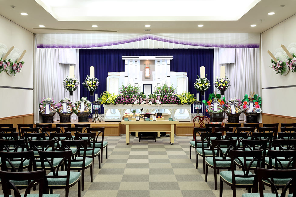A funeral altar with elegant floral arrangements and a white coffin at the center