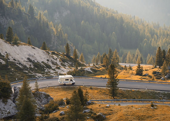 Image of an RV travelling along the road against a mountainous landscape.