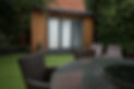 Modern timber clad garden room with grey French doors situated on a neat artificial lawn
