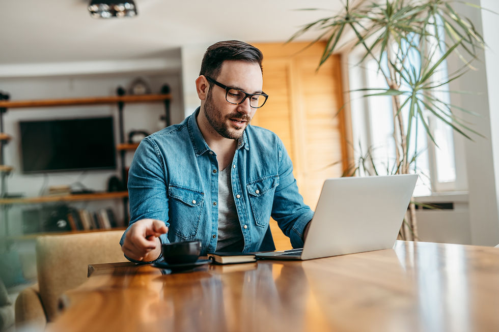 Man sitting at table working on laptop and drinking tea