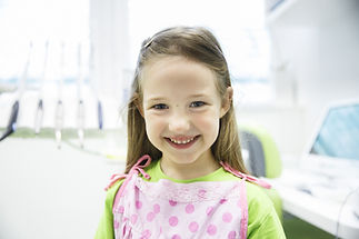 Relaxed little girl at dental office, smiling and waiting for a checkup. Early prevention,