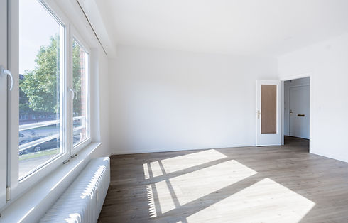 Empty room with white walls, light wooden floor, and large windows
