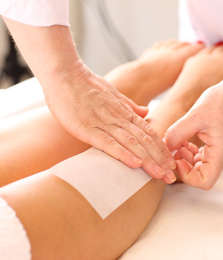 Beautician applying a paper waxing strip to a client lower leg during a treatment