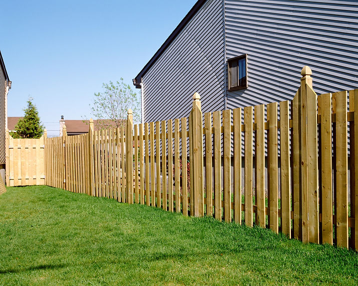 Treated timber vertical slatted wooden fence installed next to a green lawn area