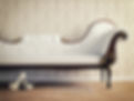 A classic white button-tufted chaise longue against patterned damask wallpaper