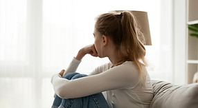 Young adult looking out window worried