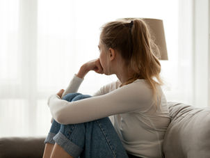 Woman sitting on couch alone looking away upset