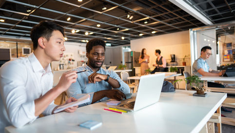 Two marketing professionals debating which content strategy they should pursue while looking at a laptop on a desk