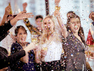 Three women at a party gathering with confetti and drinks.