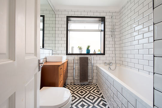 A modern bathroom with a square sink sitting on a wooden dresser with chrome tap, potted p