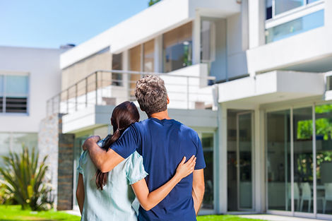 couple embracing in front of new big modern house, outdoor rear view back looking at their