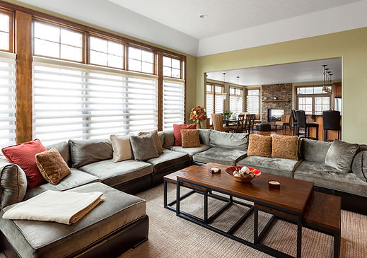 Open-plan living space featuring white window shutters and lounge furniture