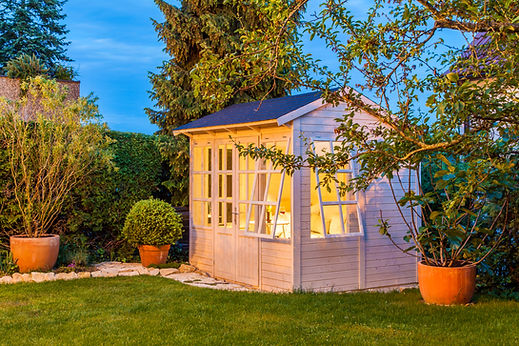 Painted wooden garden shed with windows on a manicured lawn
